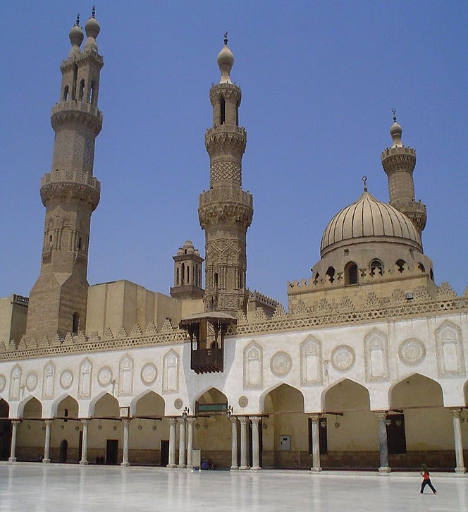 Exterior view of the Al-Azhar Mosque in Cairo, featuring its prominent minarets and dome against a clear blue sky.