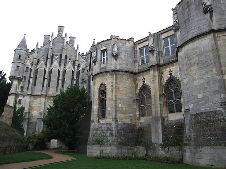A historic castle with pointed towers and intricate stonework, surrounded by greenery, showcasing medieval architecture.