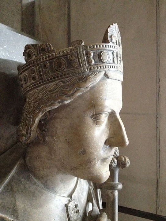 Close-up of a stone effigy depicting a crowned medieval king, showcasing intricate details of the crown and facial features.