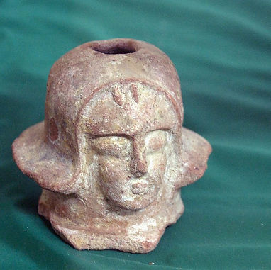 A clay figurine depicting a head with stylized features, likely from the Aksumite Empire, set against a green background.