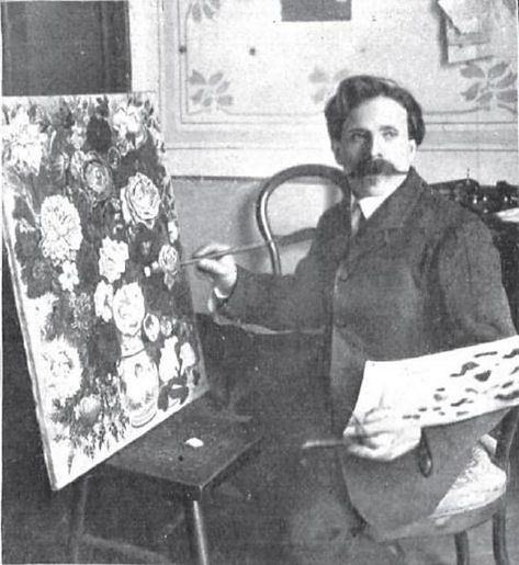 A man with a mustache sitting in a chair, painting on a canvas with floral designs.