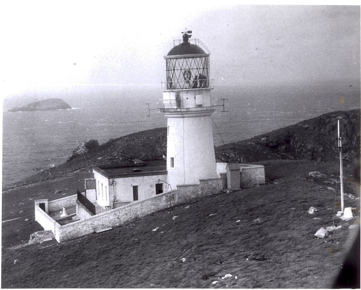 Black and white photograph of Eilean Mòr lighthouse, showcasing the structure on a coastal landscape with the sea in the background.