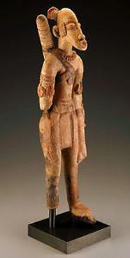 A wooden statue representing a figure from West African culture, showcasing intricate details, traditional attire, and a sculpted weapon.